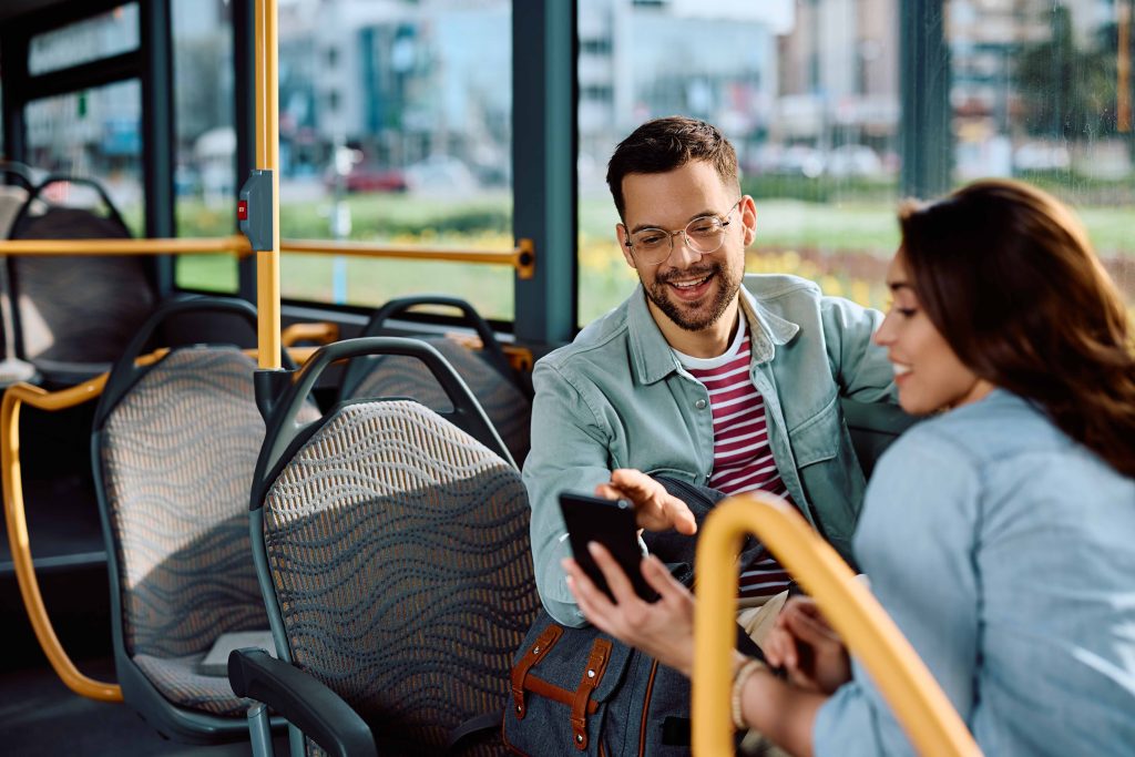Young couple using cell phone while riding in city bus.