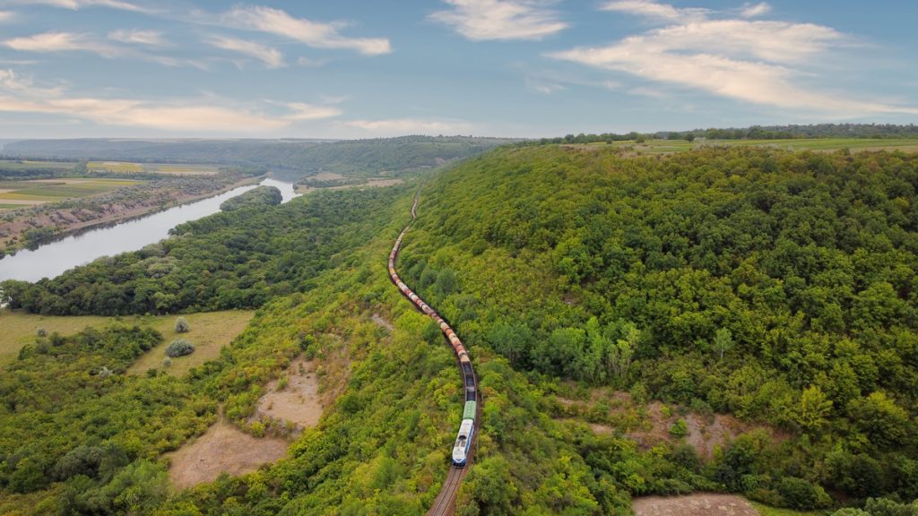 Aerial drone view of a train crossing a forest.
